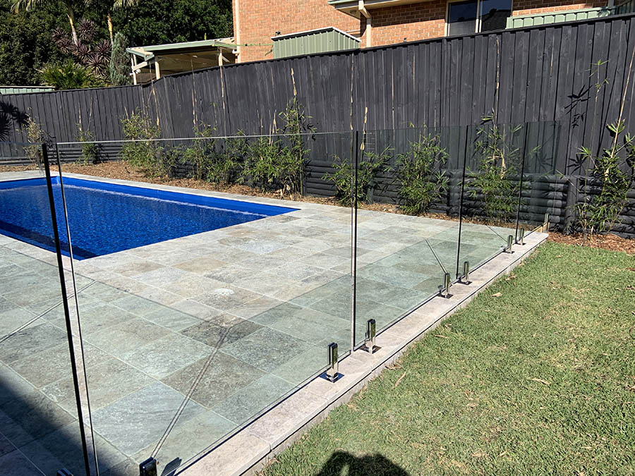 glass pool fencing separating green grass and blue pool in central coast